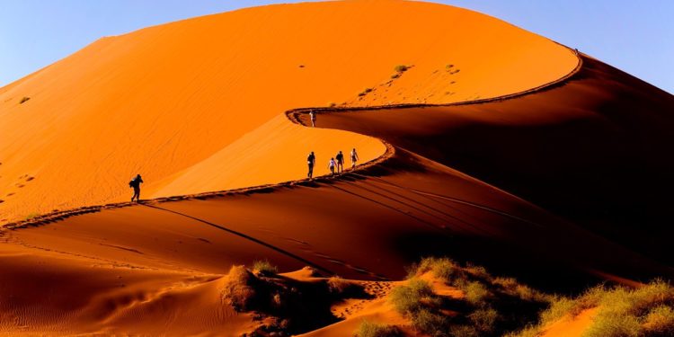 Hikers on the crest of a red dune at Sossusvlei, Namibia